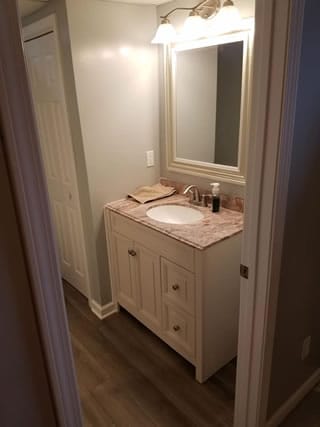 Installation of a new bathroom vanity including mirror and new flooring also installed.